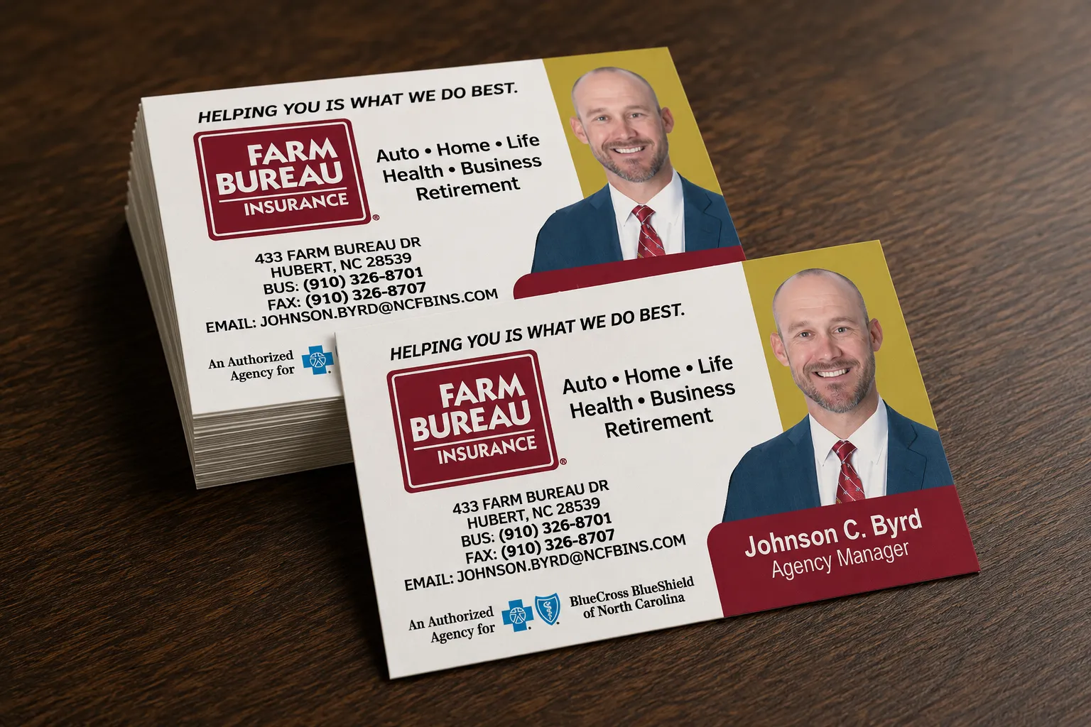 A stack of Farm Bureau Insurance business cards on a wood desk, showing an agency manager's photo, contact details, and red-and-gold branding.
