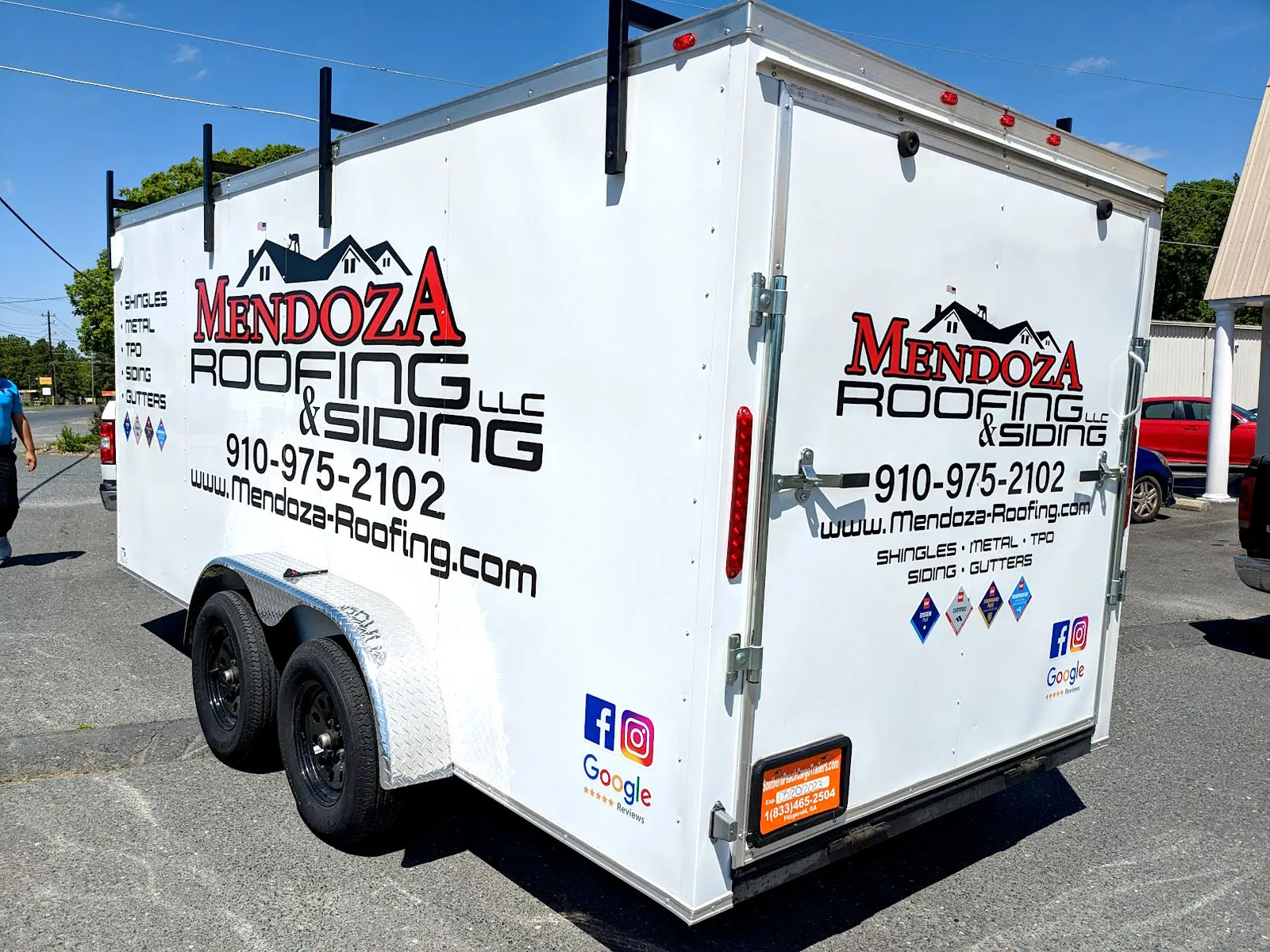 A white enclosed trailer lettered on the side and rear doors with Mendoza Roofing and Siding logos, phone number, and certification badges.