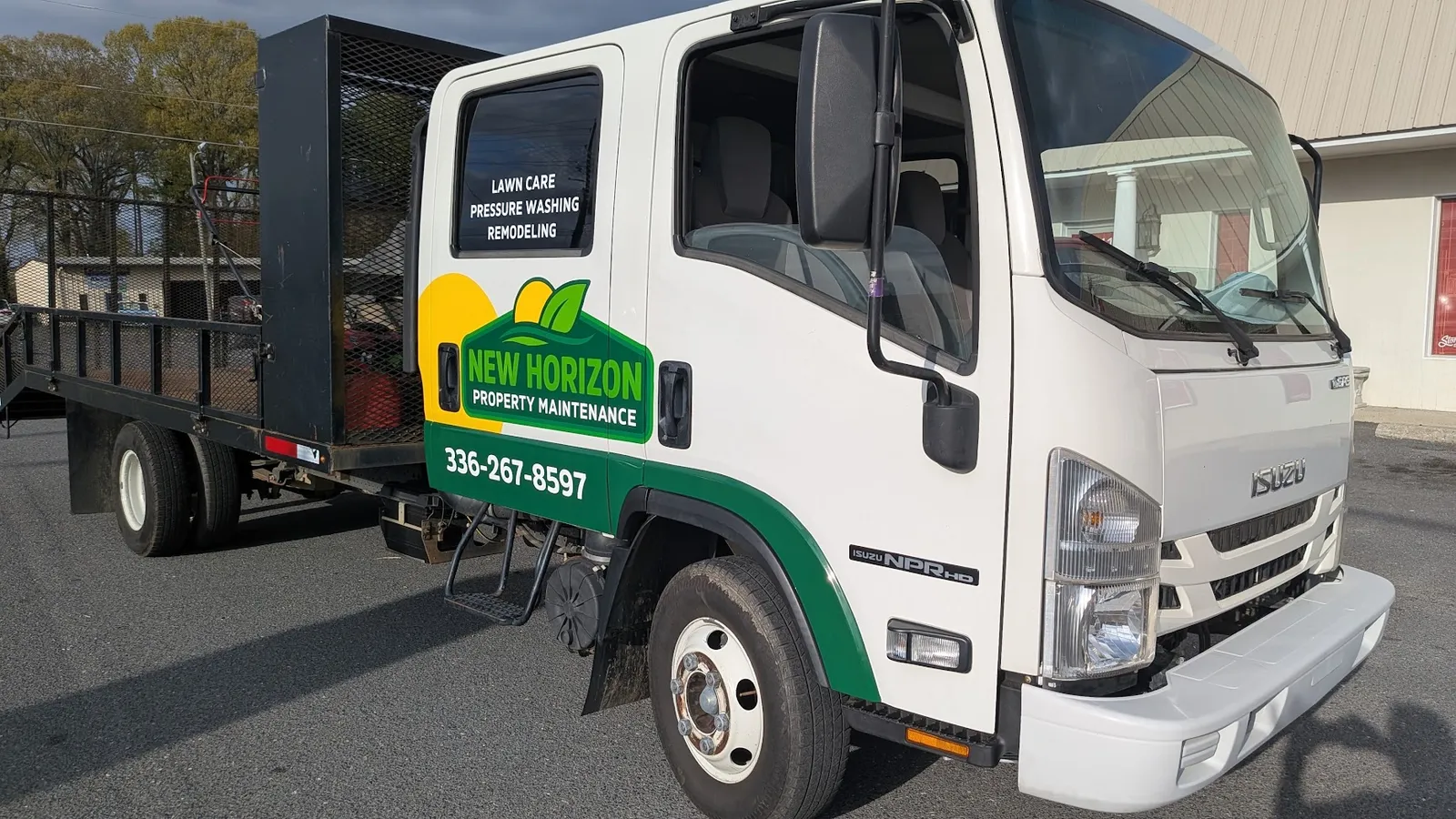 A white Isuzu flatbed work truck with green and yellow New Horizon Property Maintenance logo and service lettering on the cab.